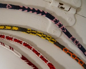 Fingerloop braids of various types with pickup patterns, made by Ingrid Crickmore.